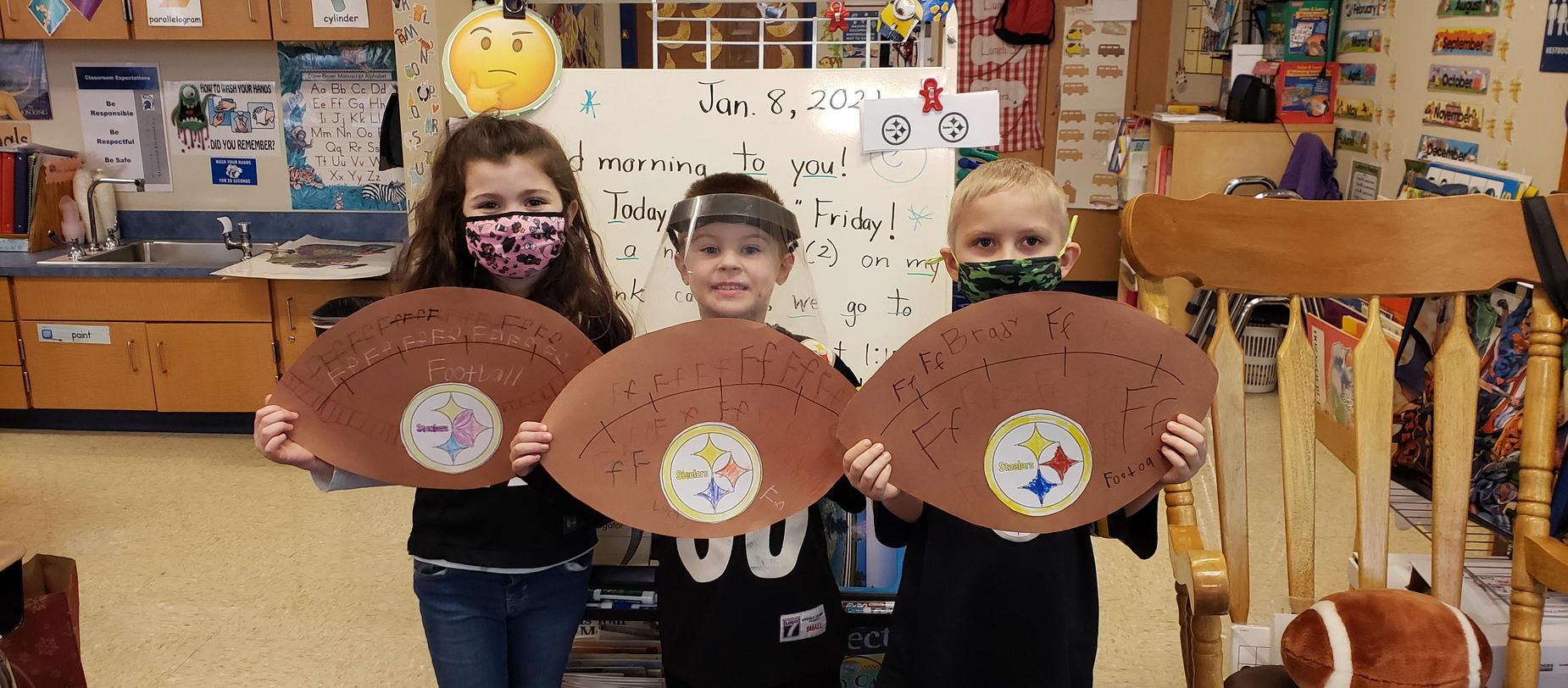 students posing with footballs