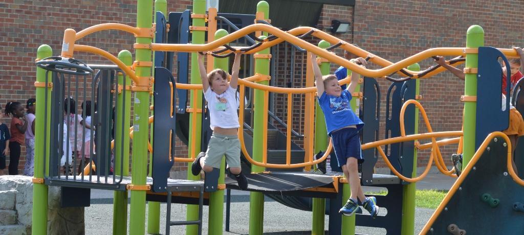 2 boys hanging from monkey bars