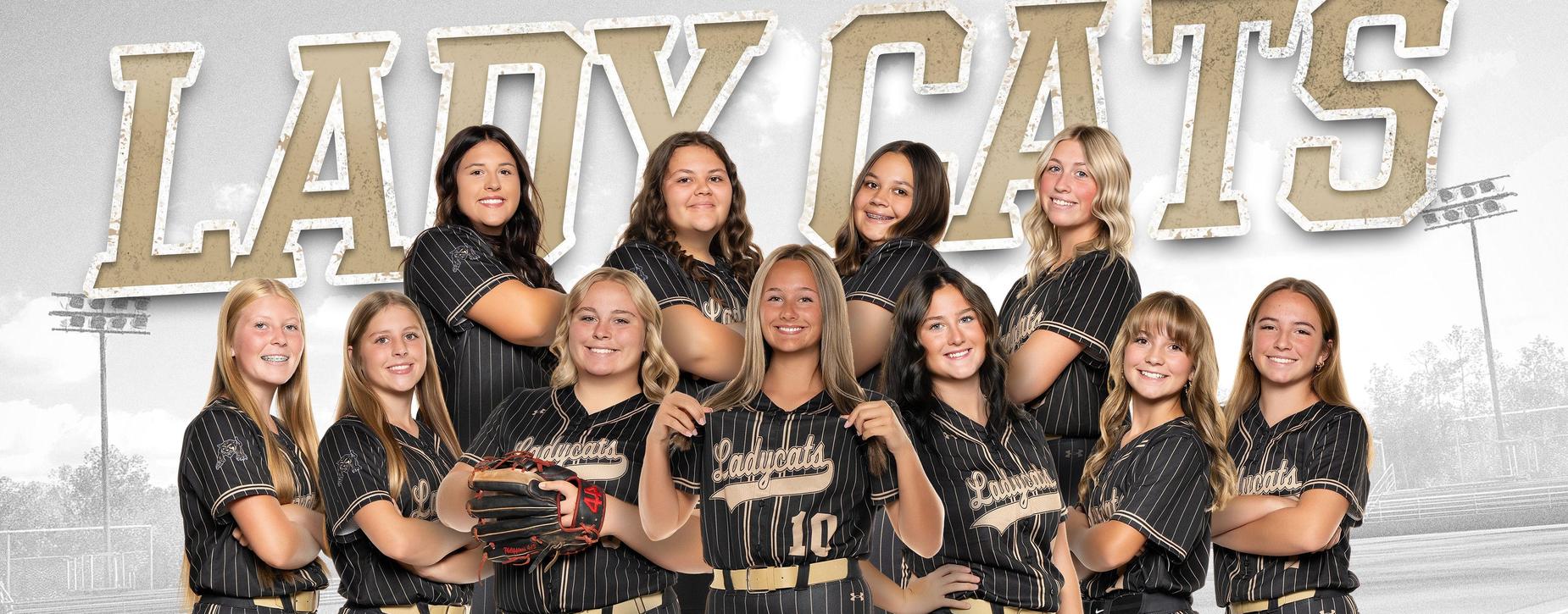 Fredericktown softball team members in black and gold uniforms smiling together.