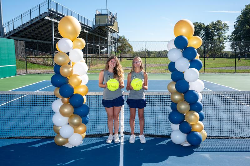 2 girls standing next to columns of balloons