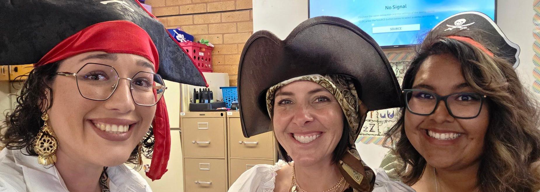 Three women dressed in pirate costumes, smiling with hats and accessories.