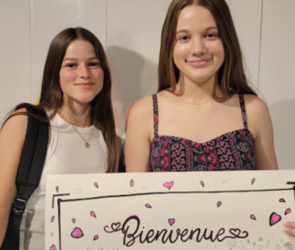 Two girls holding a Bienvenue sign