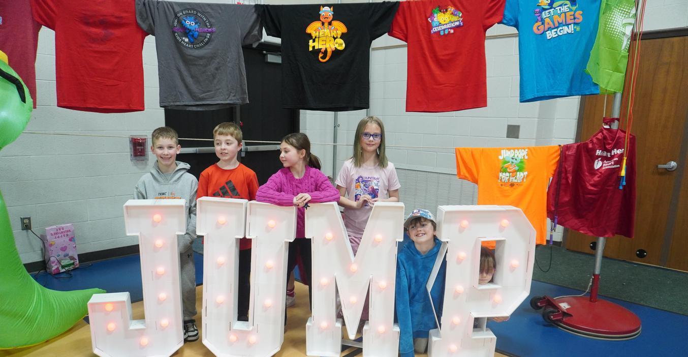 Students pose for a picture behind the "JUMP" sing at the Kids Heart Challenge event.