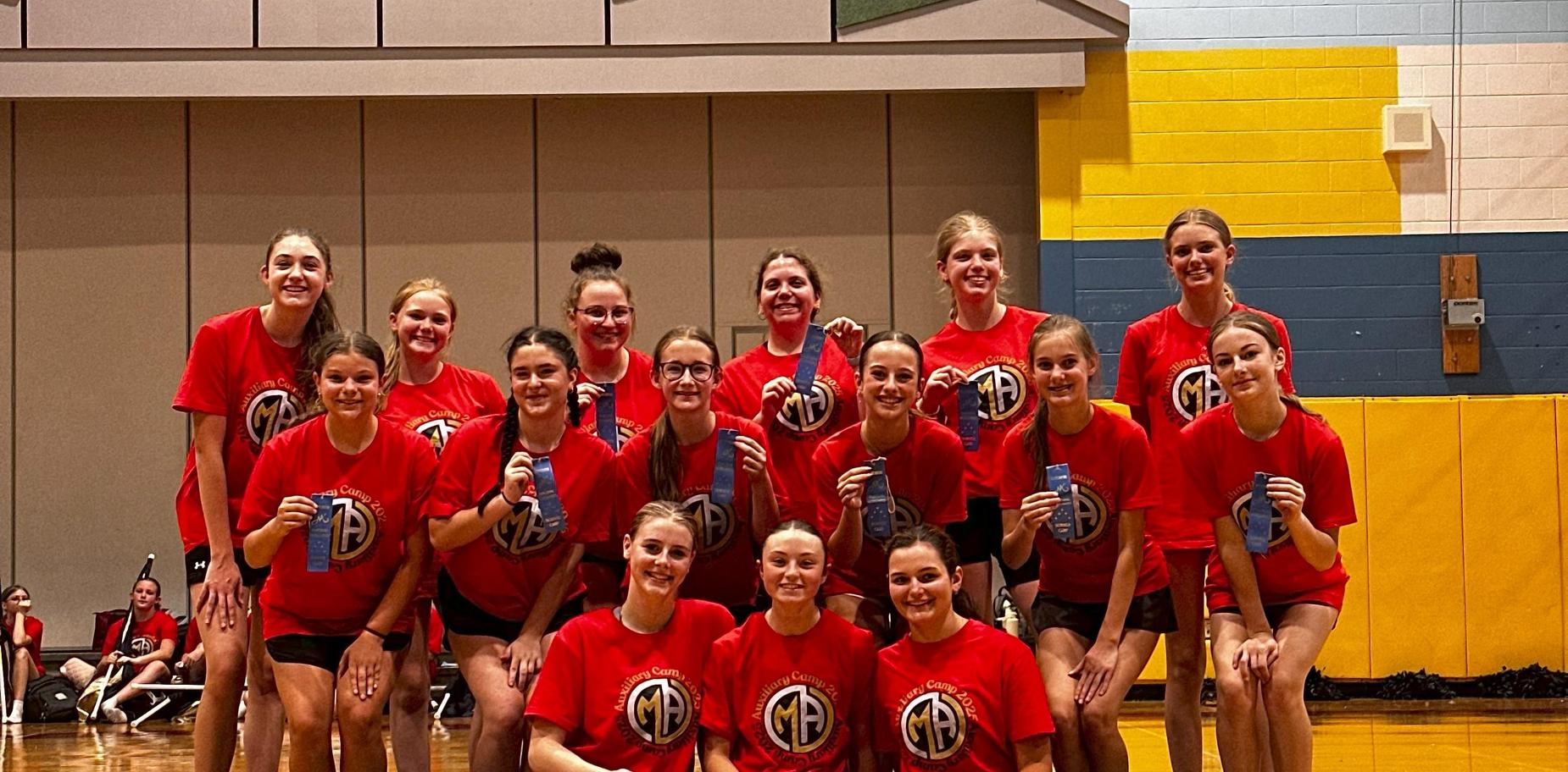 group of girls in red t-shirts holding blue ribbons and posing