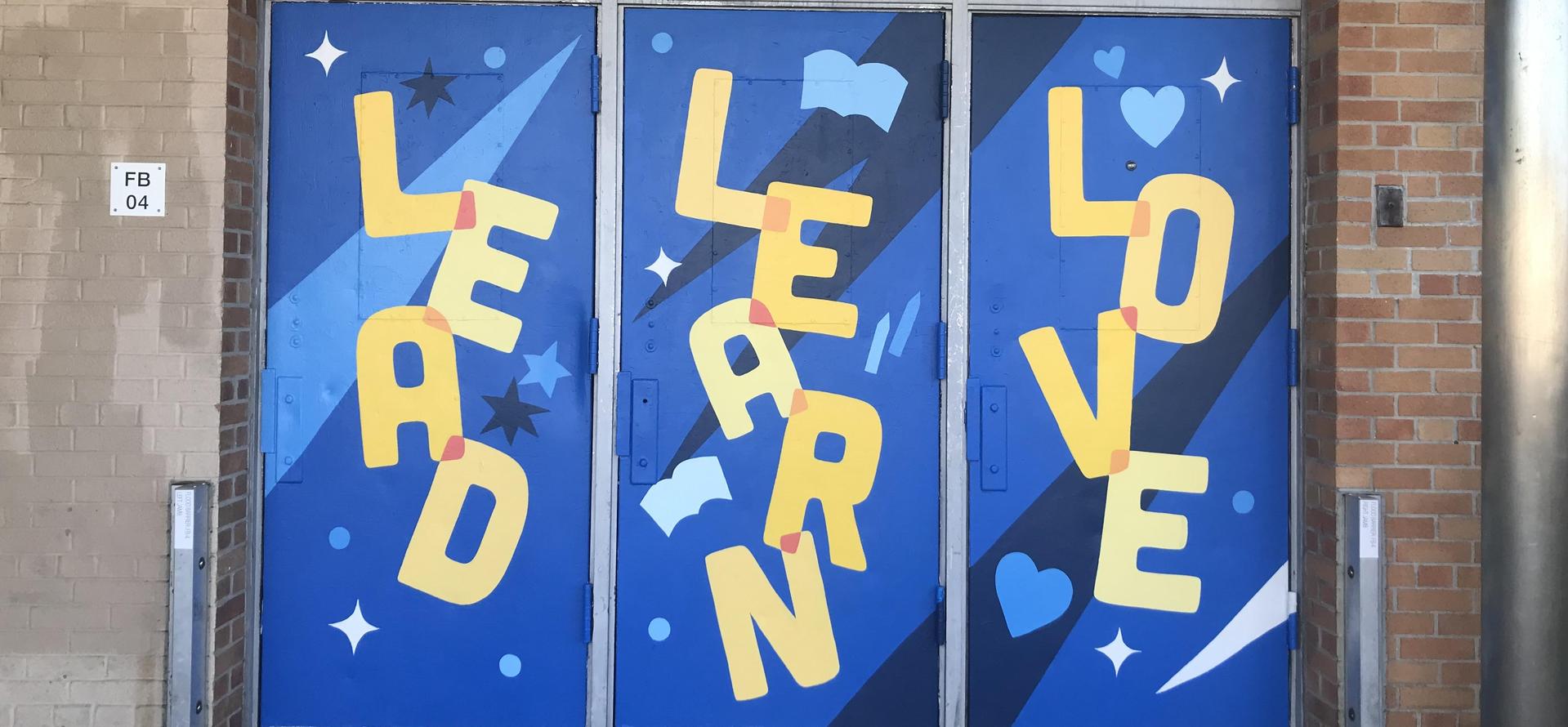 Colorful mural on wooden doors featuring the words 'LEAD', 'LEARN', and 'LOVE'.