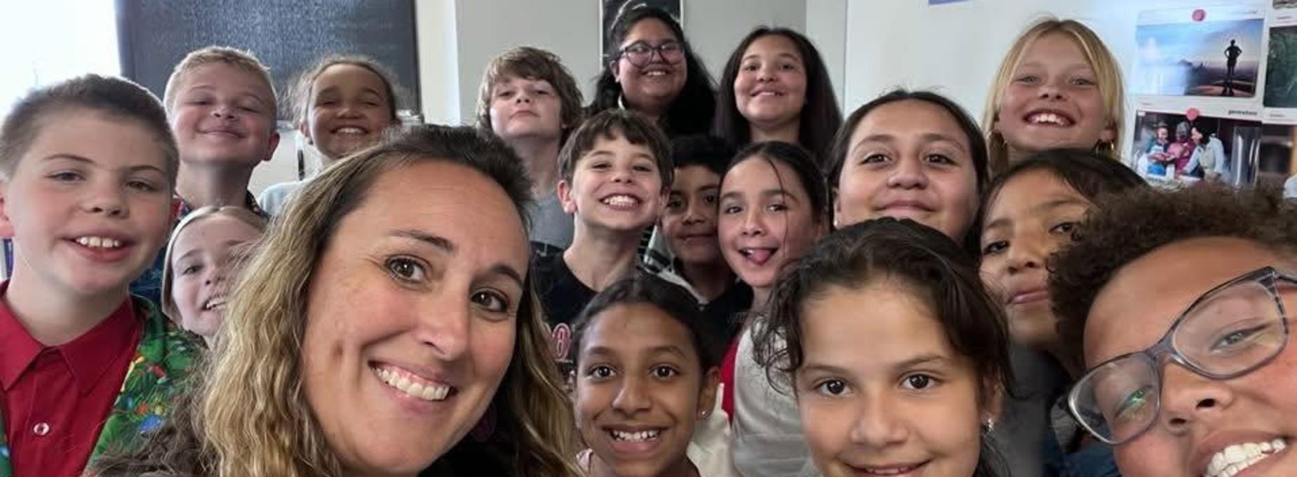Smiling group of students and teacher posing for a selfie.