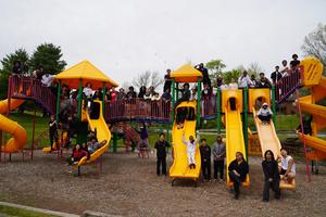 Large group of people posing on and around playground equipment.