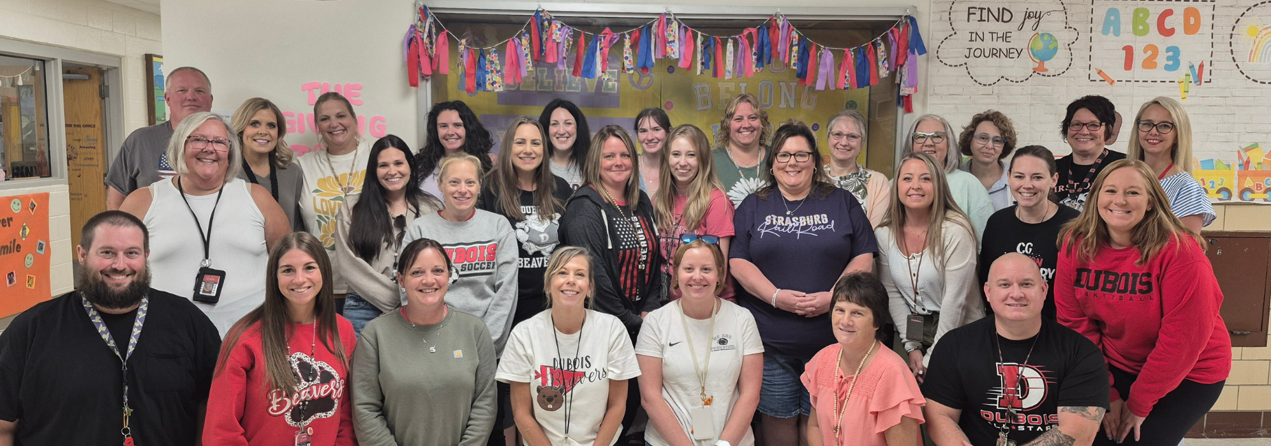 Group of staff members smiling together in a school setting.