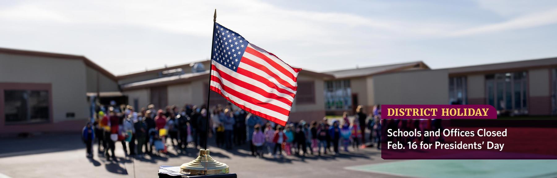 Photo of students lined up on a school playground with the American flag in the foreground, and the words: District Holiday, Schools and Offices Closed Feb. 16 for Presidents' Day.