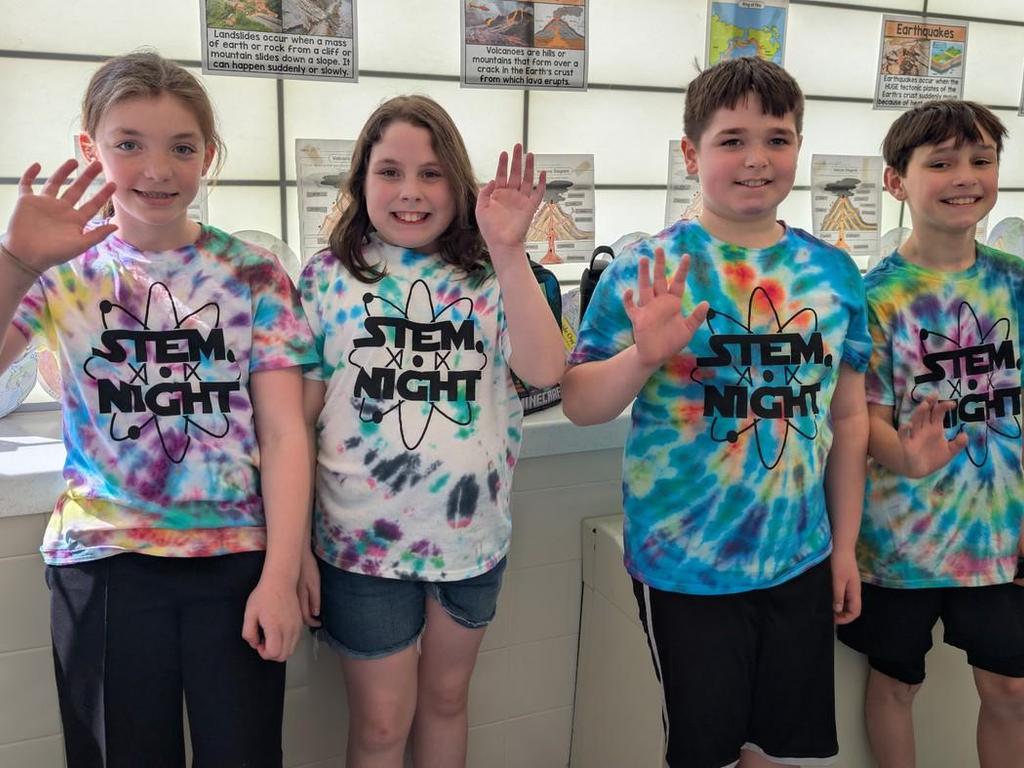 Four students waving and wearing tie-dyed STEM NIGHT t-shirts.
