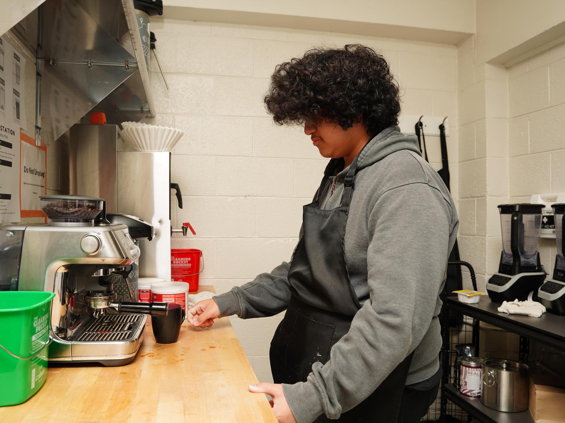 A student making coffee in the Coffee Cafe
