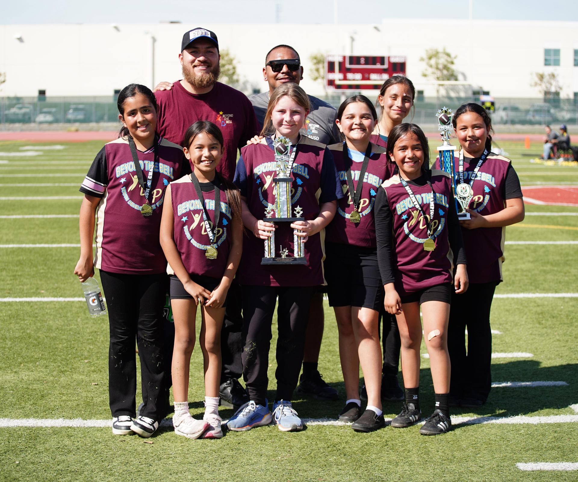 students posing with coach and trophy