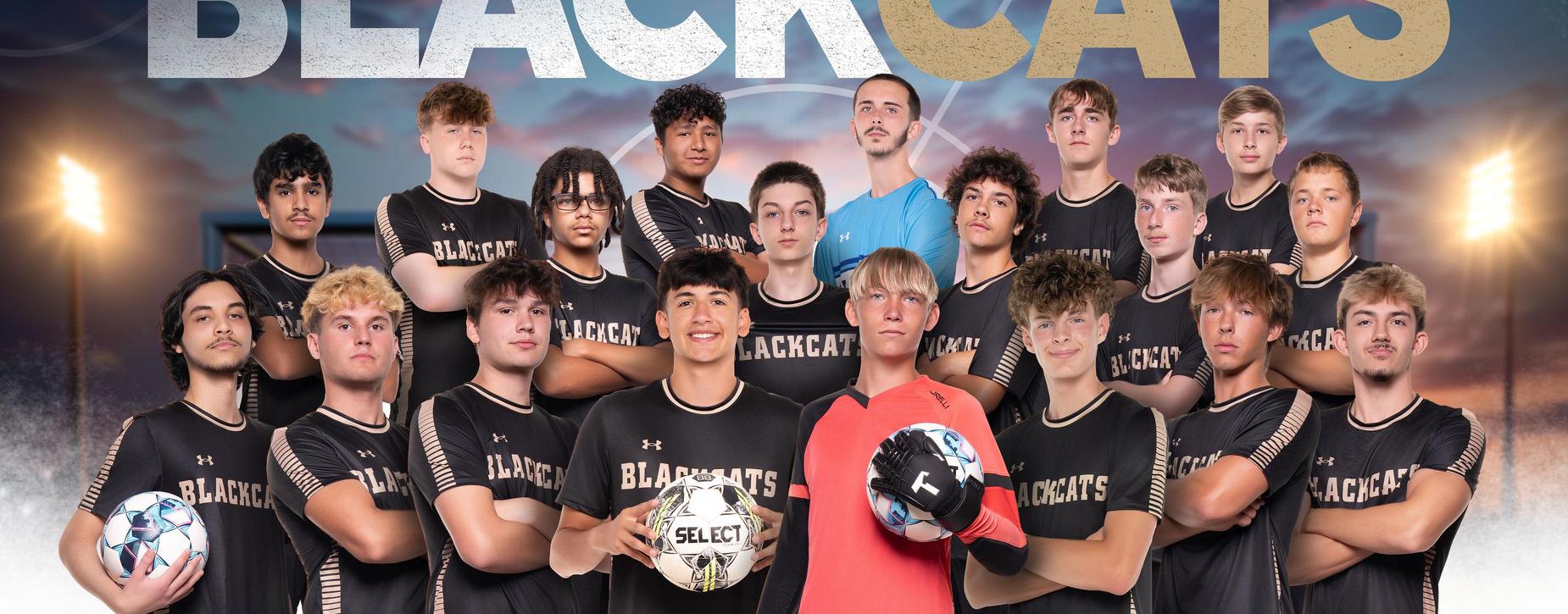 Group of male soccer players posing with soccer balls.