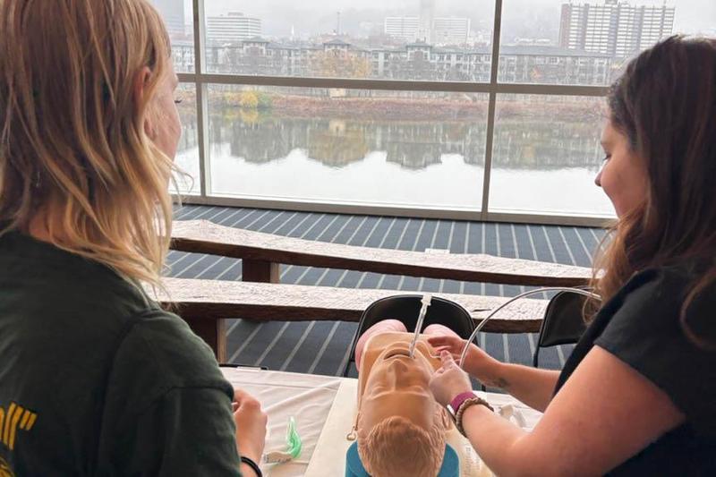 Freshman Midnight Stout (left) learns about patient procedures used by a UPMC certified registered nurse anesthetist while utilizing an airway management trainer