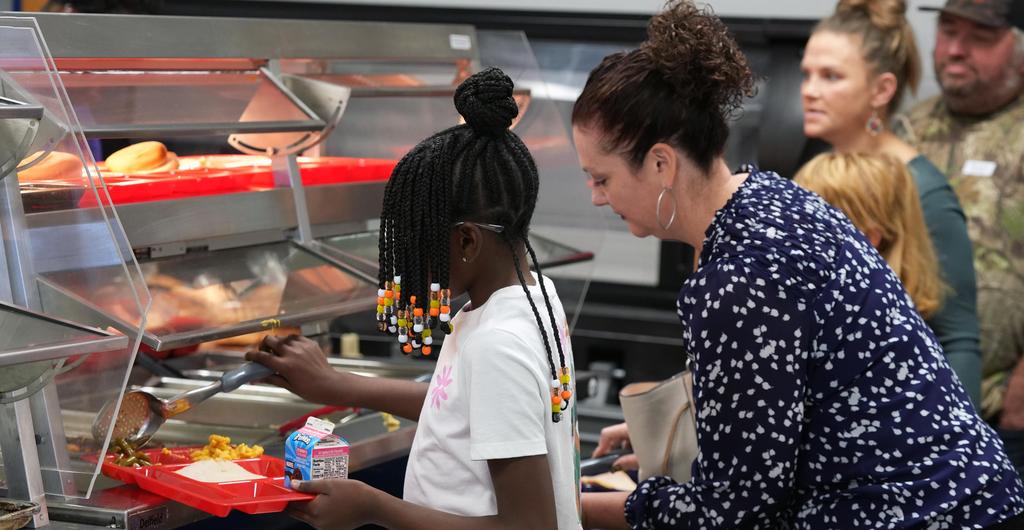 Adults and students pick up trays in the lunch line