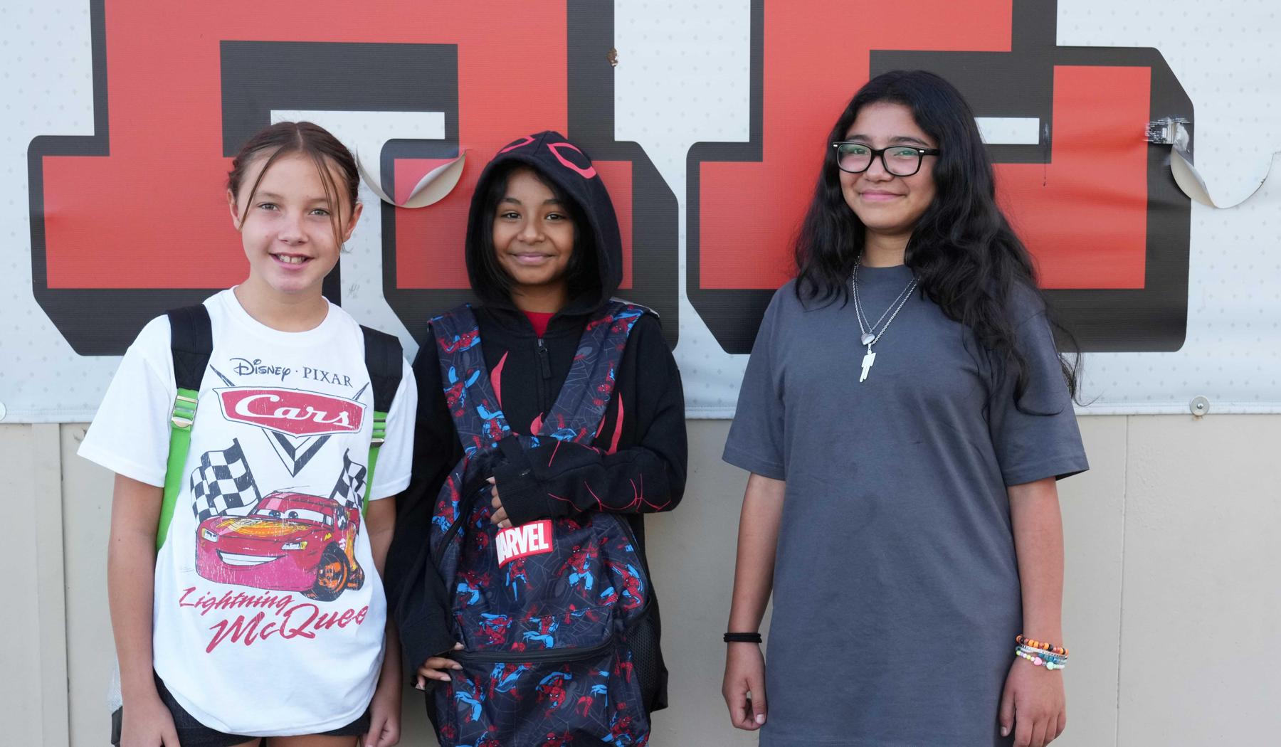 Three girls standing by "Tigers" sign at SJE.
