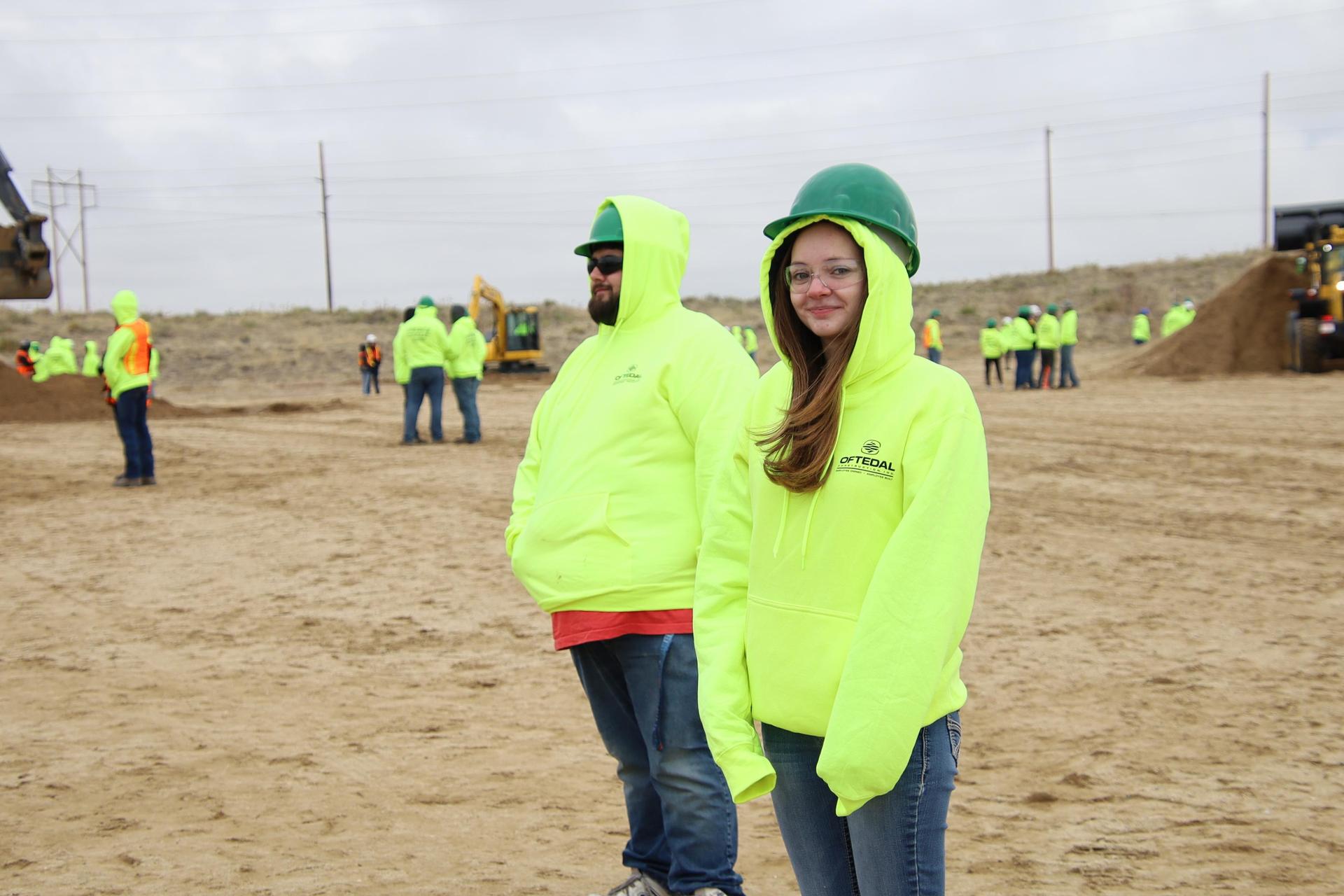 high school girl in construction hat smiling at the camera in construction site