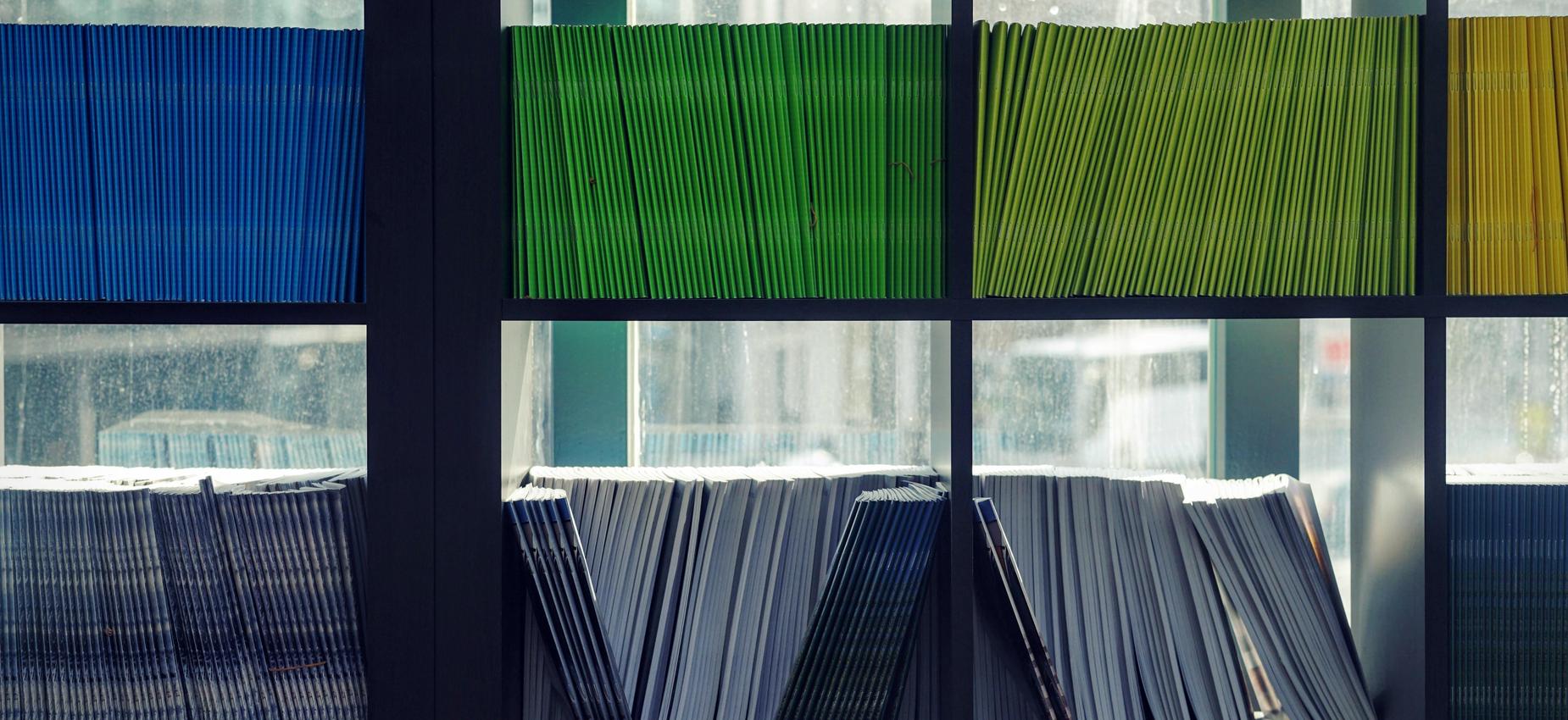 Colorful rows of stacked magazines and journals in a library setting.