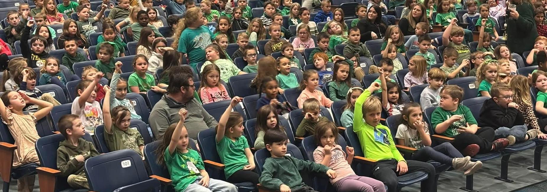 Students in auditorium chairs watching an assembly.