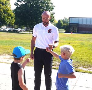 Mr. Sleeman gives fist bumps to students at recess.