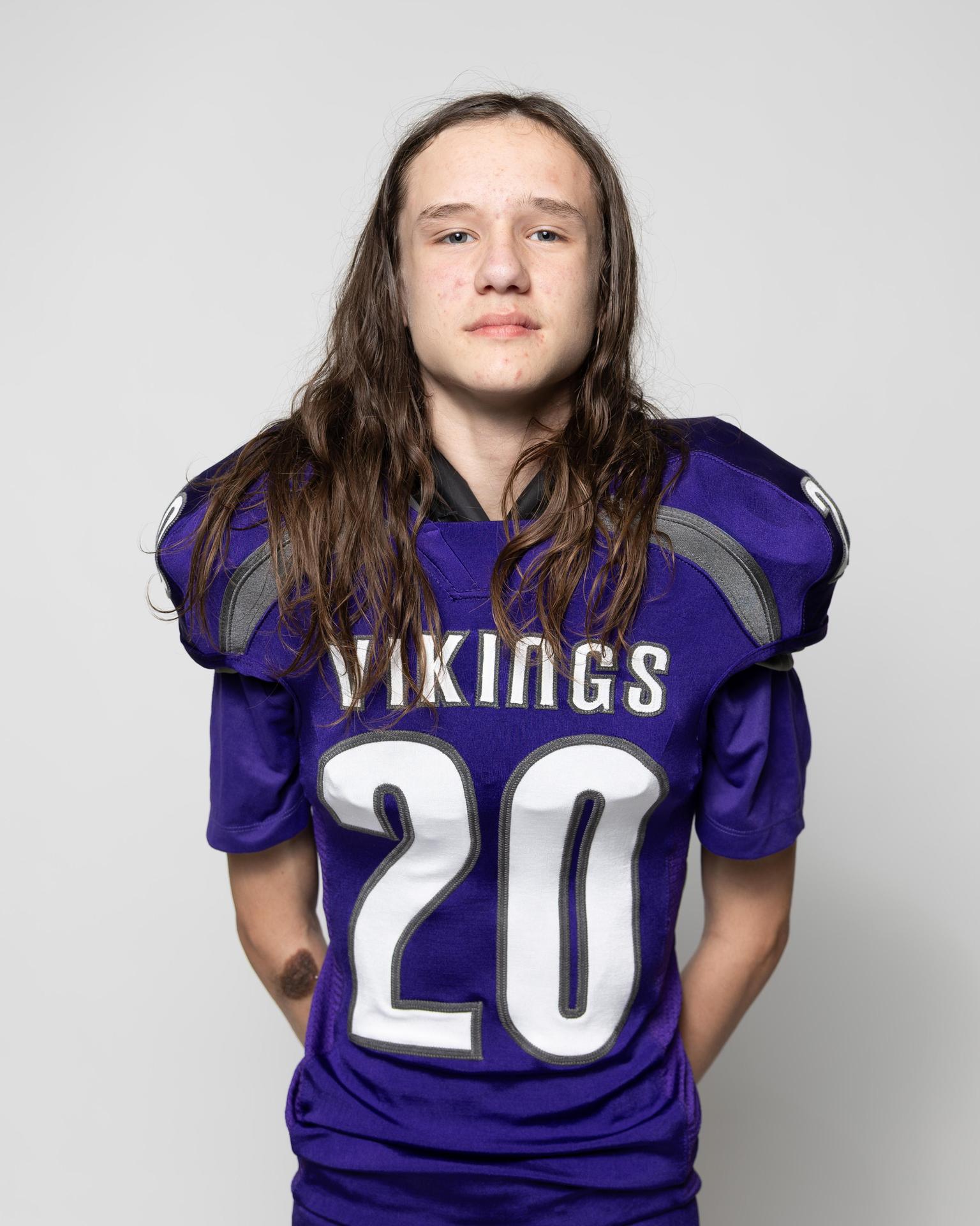 Young football player wearing a purple Vikings jersey, posing confidently.