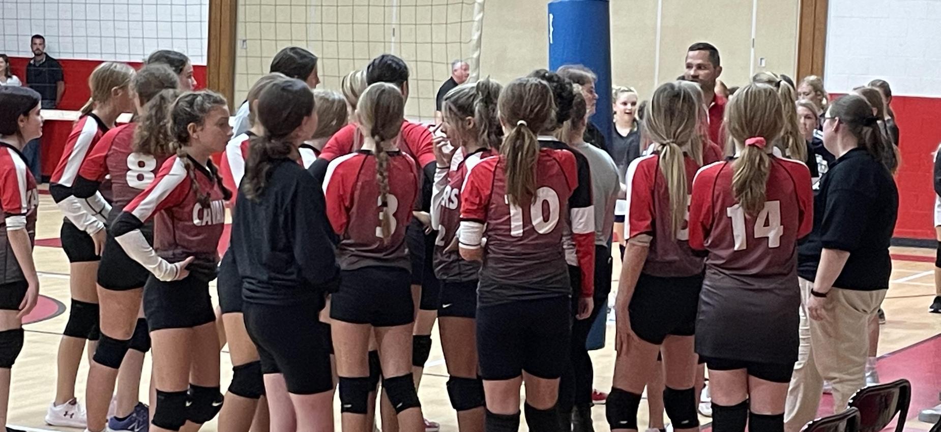 Volleyball players gather in a huddle.