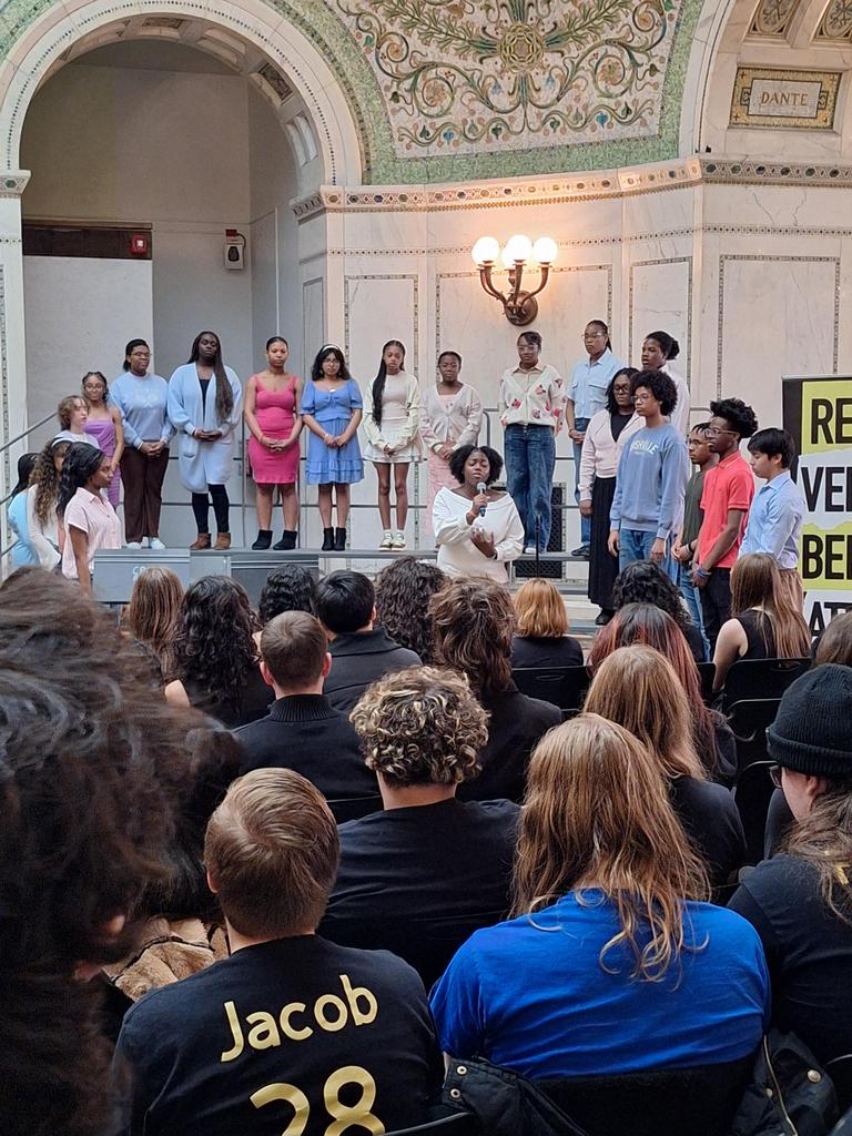 Choir singing in front of seated crowd.
