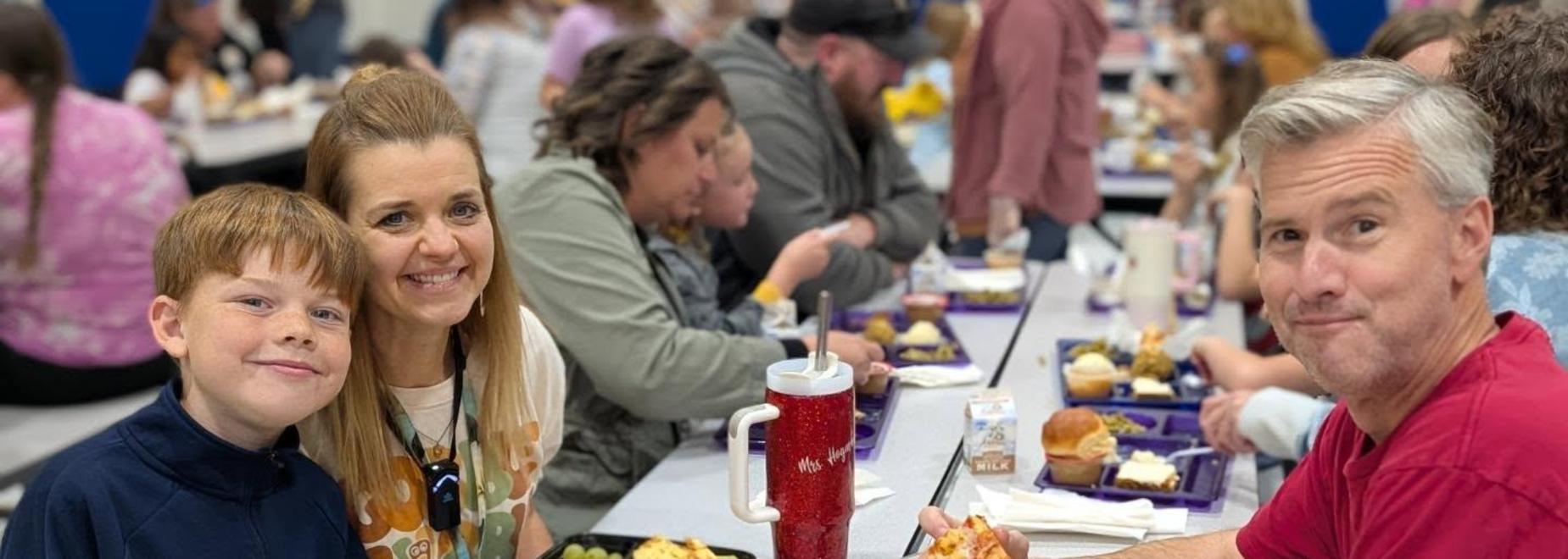 Family enjoying pizza at a table in a communal setting.