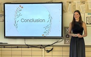 Presentation with a woman standing beside a screen displaying 'Conclusion'.