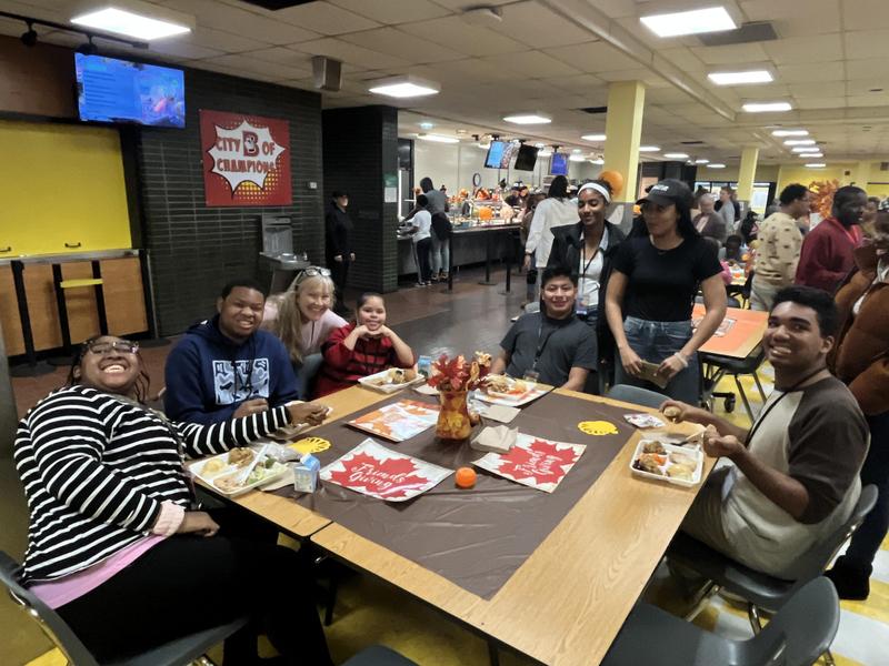 Students and staff sitting and standing around a table