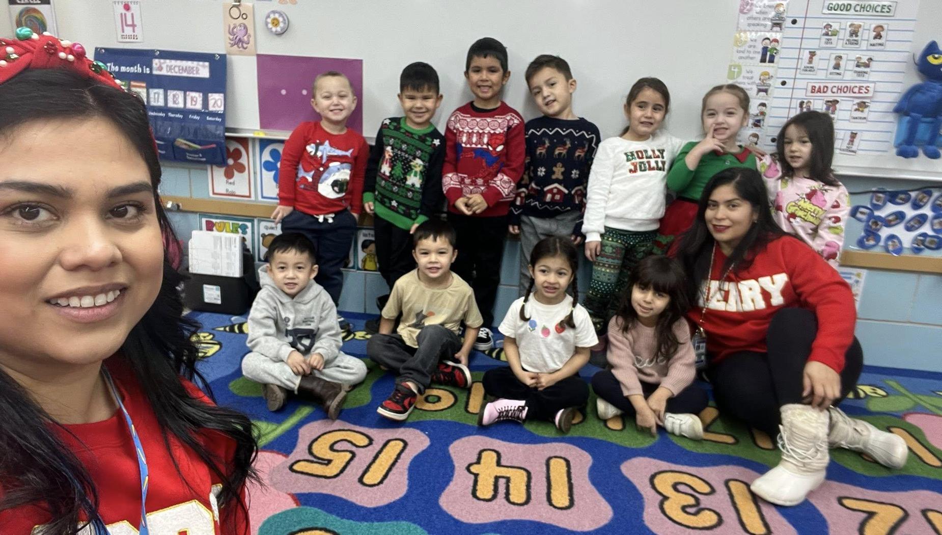 Class of children and a teacher smiling together in a classroom setting.