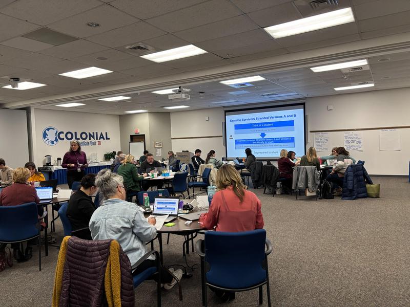 professionals sit at tables and listen to presentation