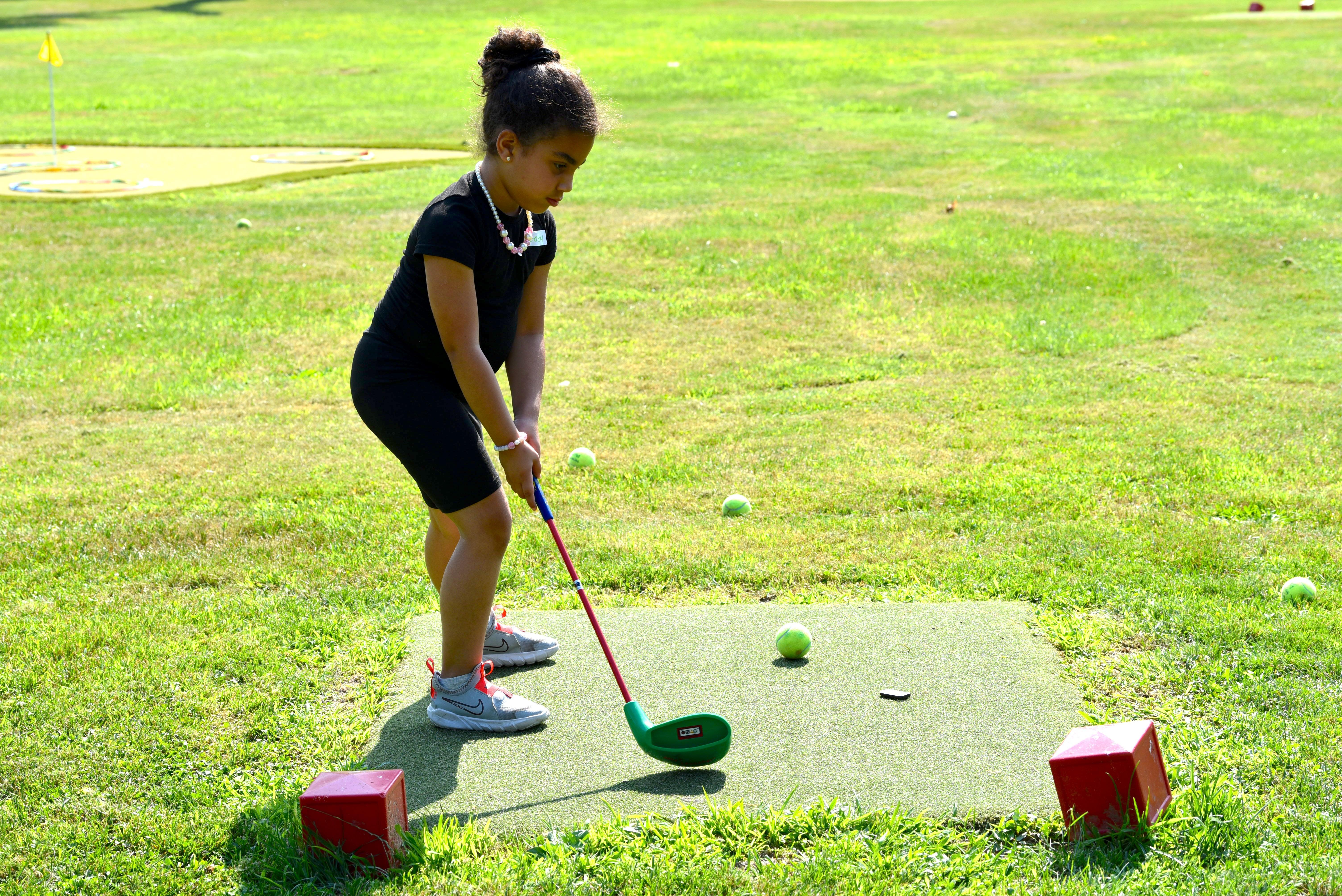 a little girl is about to swing a golf club
