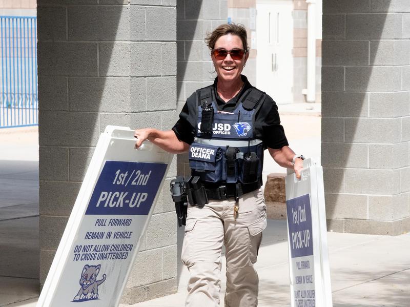 school resource officer carrying signs for parent pickup