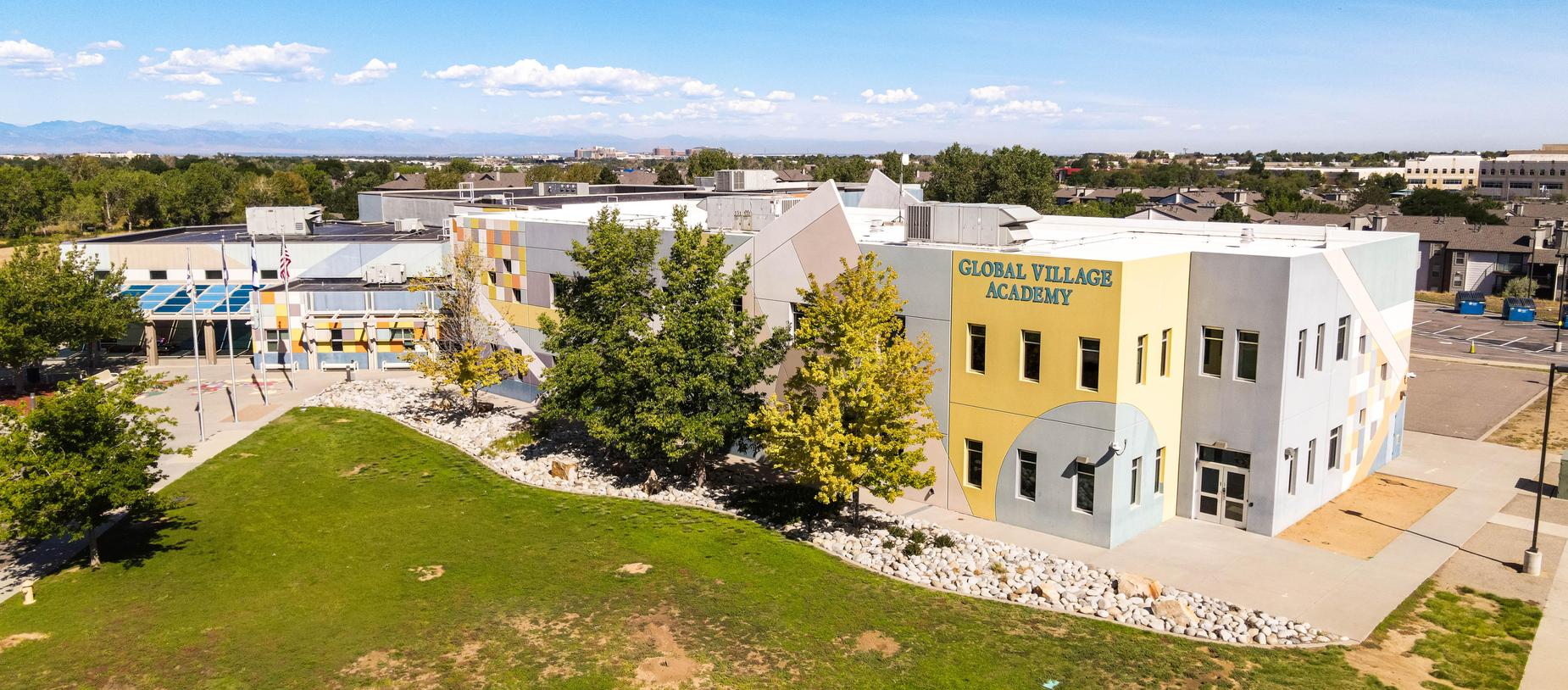 Aerial view of Global Village Academy's colorful building and surrounding landscape.