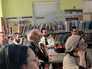 A parent chuckling at something Rabbi Schwarzmer said.