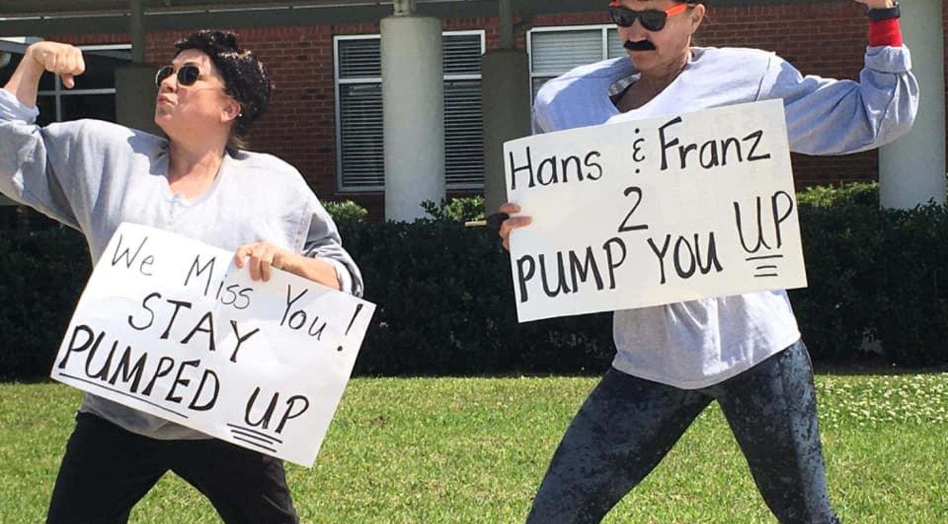 Teachers pose with signs before drive-thru parade.