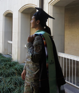 Hayley walking in military outfit while holding her graduation gown