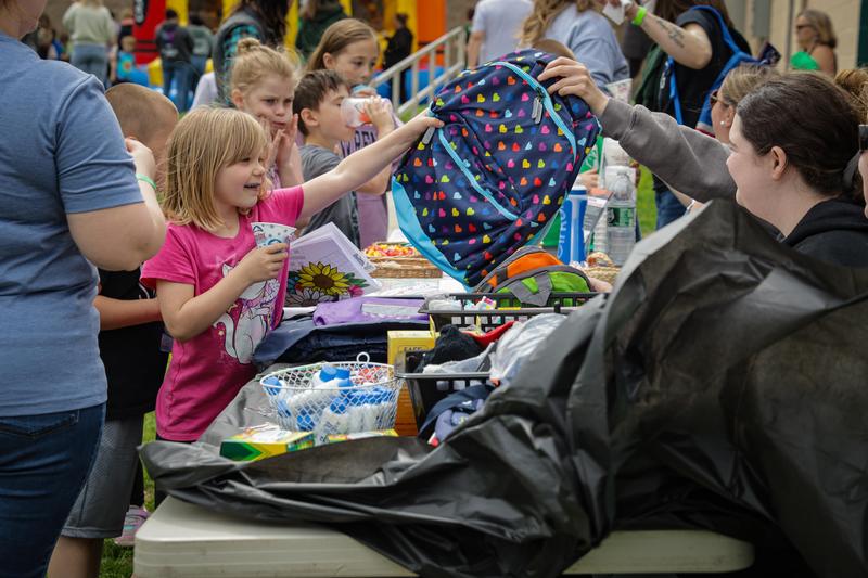 An MCS student is handed a backpack.