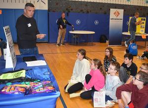 A speaker presents to students while they listen attentively on the floor.