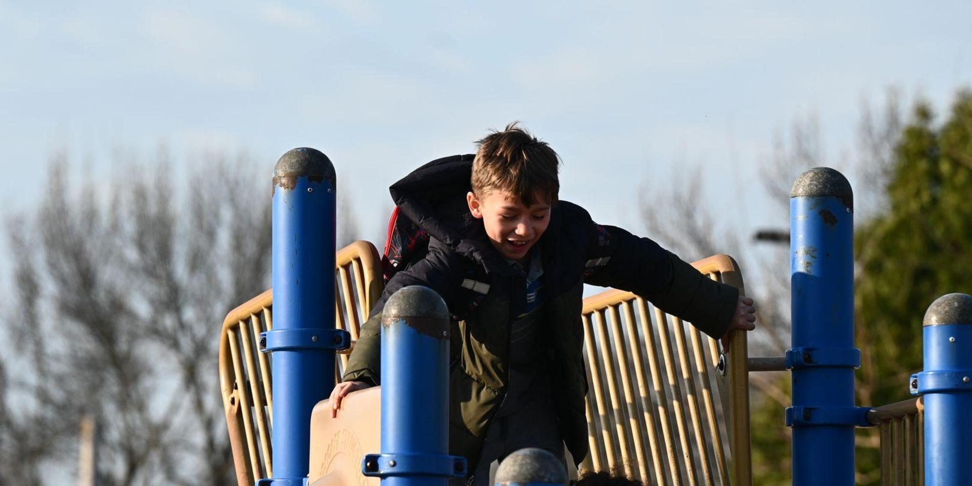 Boy smiling while climbing on a playground structure.
