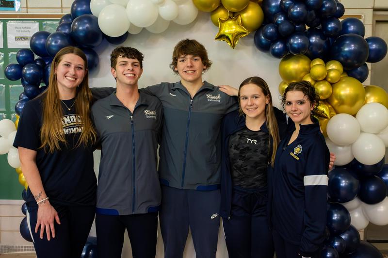 swimmers stand under a balloon arch in Knoch warm ups