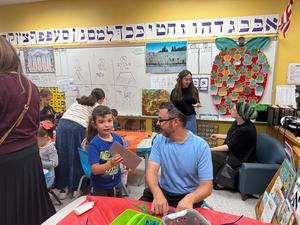 A kindergarten boy and his father work together to make sukkah decorations.