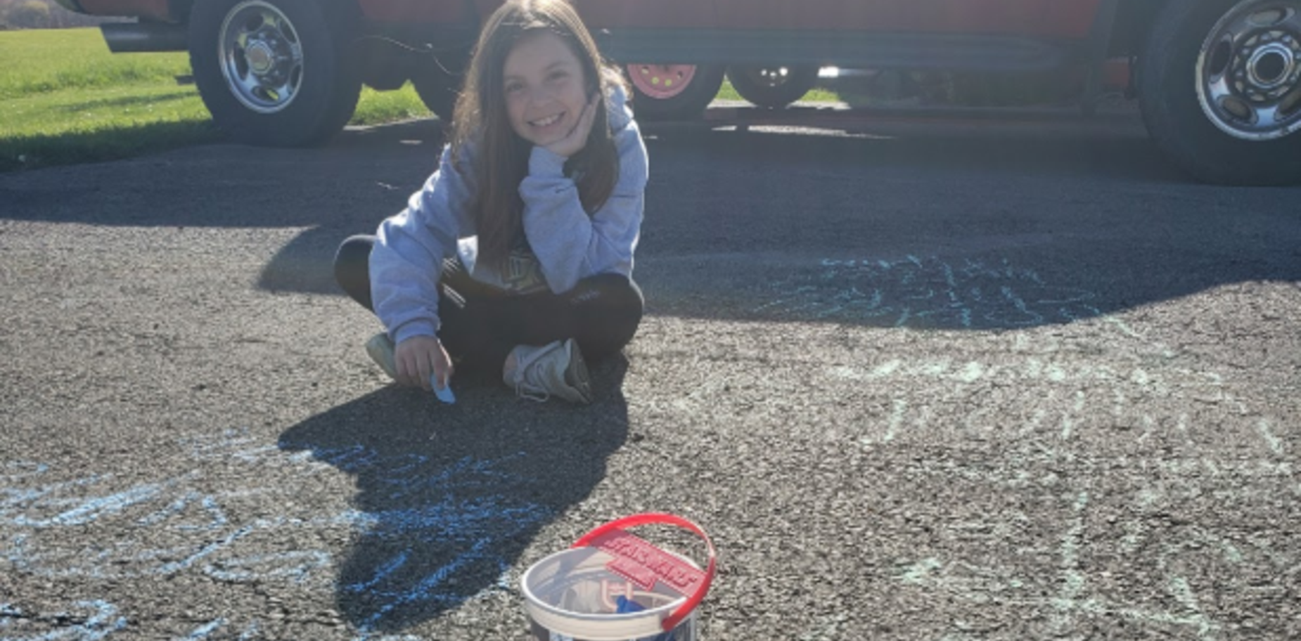 Student writing spelling words in driveway