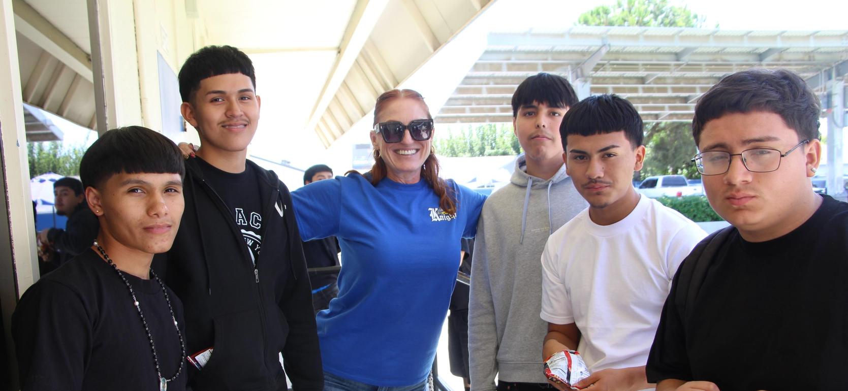 A group of six young people, including a woman, outdoors holding snacks.