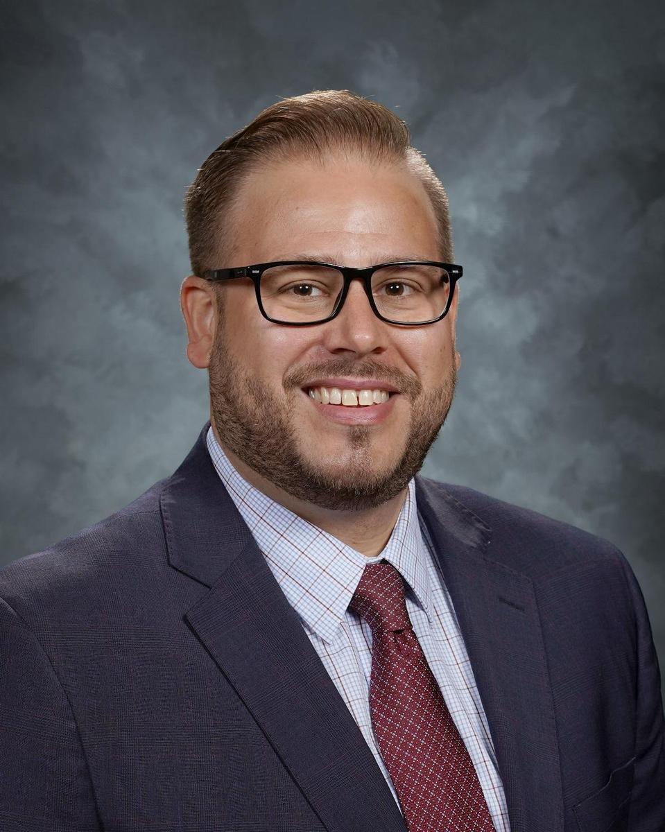 man with glasses and beard smiling in suit