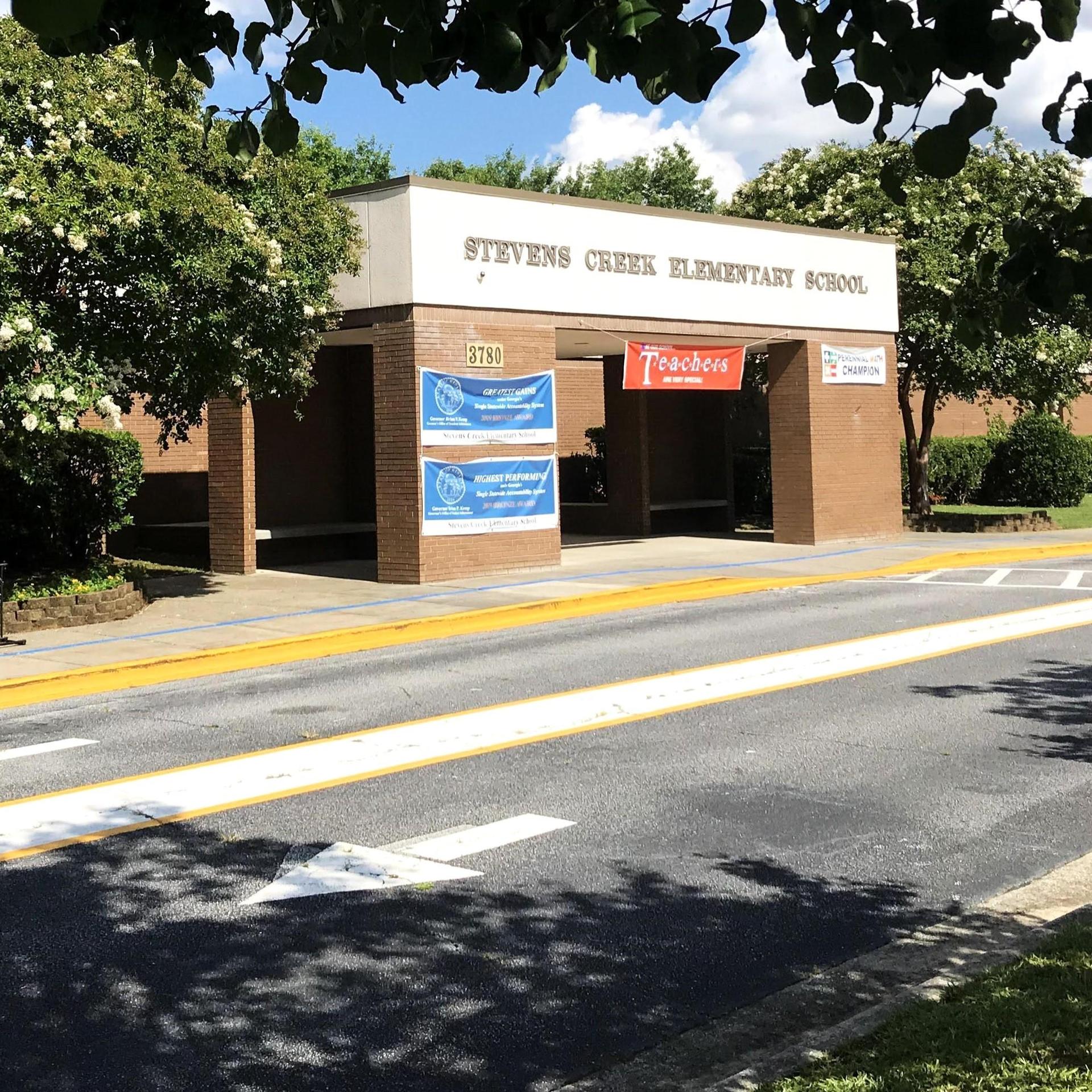 Entrance of Stevens Creek Elementary School with a sign and greenery.