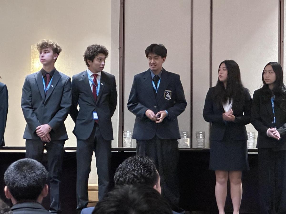A group of students in formal wear standing on stage at an event.