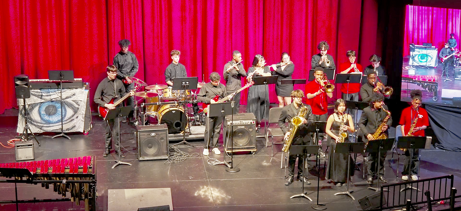 A jazz band performing on stage with various instruments and musicians in concert attire.
