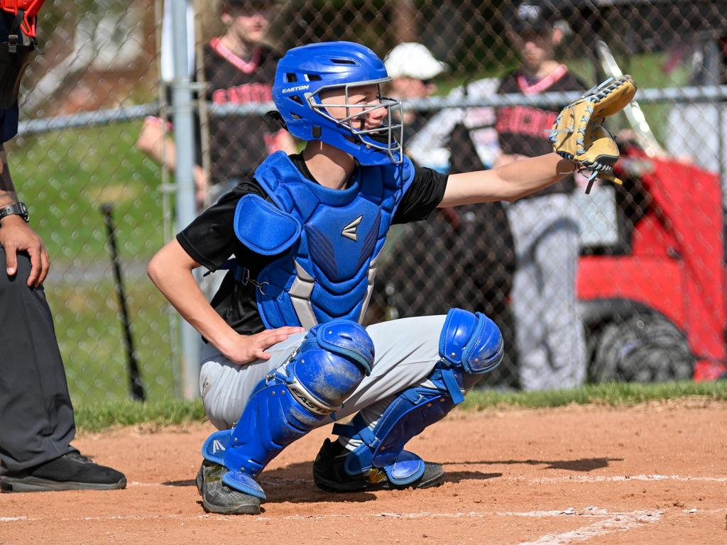 A catcher in position in the catchers box on the field.